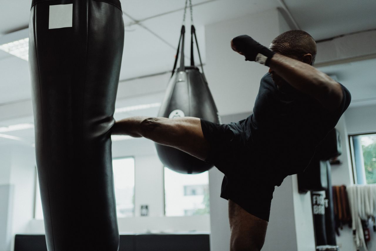 services-01 An athlete demonstrating powerful kicks in an indoor gym, focused on fitness and strength.